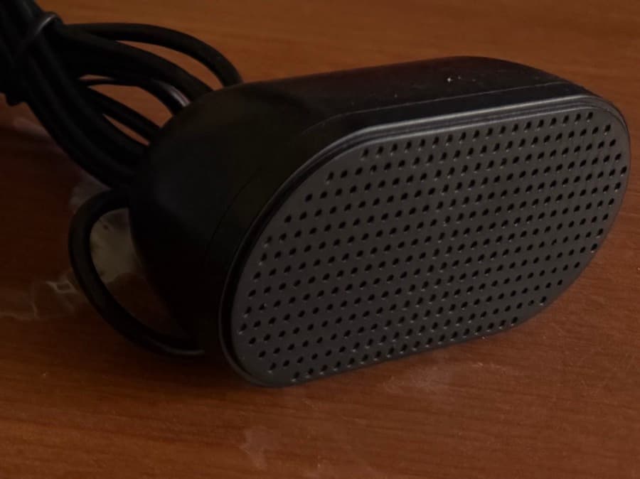 A small black USB-powered desktop speaker with its cable coiled beside it